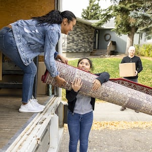 woman and her family putting rug in moving truck
